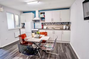 a kitchen with white cabinets and a table and chairs at Little Garden View in Saint Albans