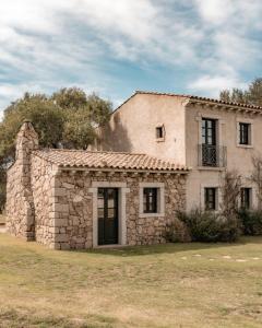 uma velha casa de pedra sentada em cima de um campo em Stazzo Lu Ciaccaru em Arzachena