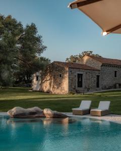 a swimming pool with two chairs and a house at Stazzo Lu Ciaccaru in Arzachena