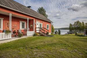 a red house with a large yard next to a lake at Majestic 3 Bedroom Villa With Sauna in Rovaniemi