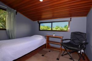 1 dormitorio con 1 cama, 1 silla y 1 ventana en Villa Golondrina Cabaña rodeada de Naturaleza, en Monteverde