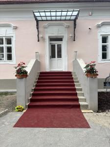 uma escada que conduz a uma casa branca com um tapete vermelho em Kaštieľ Ladce 