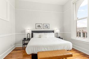 a white bedroom with a bed and two windows at The McKey in Valdosta