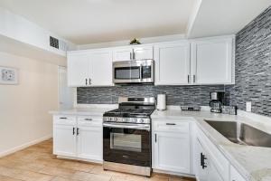 a kitchen with white cabinets and a stove top oven at Sunny Yuma Vacation Rental with Private Pool! in Yuma