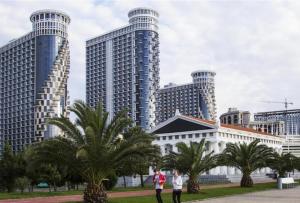 duas pessoas andando em frente a prédios altos em Orbi Sea Tower Apartment em Batumi