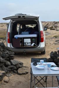 a van with its back door open with a table and chairs at FurgoCamper Van H1 in Tetir