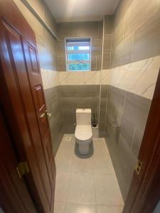 a small bathroom with a toilet and a window at Meru Heights in Meru