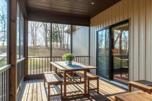 een afgeschermde veranda met een houten tafel en banken bij LUXE Alpine Getaway Lodge with Hot Tub by Sarah Bernard in Innsbrook