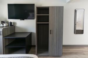 um quarto com uma televisão e um armário de madeira em The Farmstead Hotel em Caruthersville
