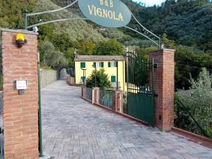 a driveway leading to a yellow house with a gate at B&B Vignola in Levanto