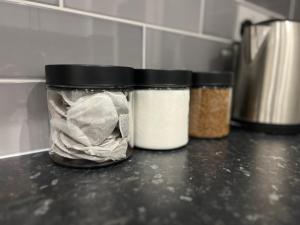 three jars of spices sitting on a counter in a kitchen at Oakwood Suite - Sleeps 5 - Contractors - Smart TVs in all rooms in Cheshunt +10 photos