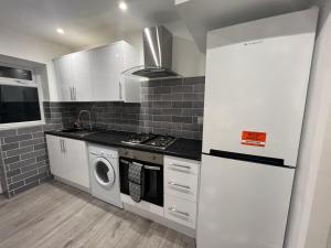 a kitchen with a stove and a washer and dryer at Oakwood Suite - Sleeps 5 - Contractors - Smart TVs in all rooms in Cheshunt