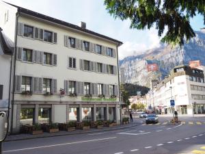 un bâtiment situé sur le côté d'une rue avec une montagne dans l'établissement Hotel Stadthof Glarus, à Glarus