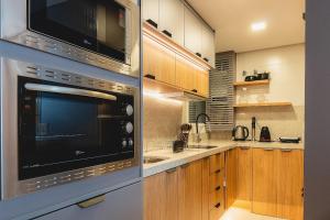 a kitchen with stainless steel appliances and wooden cabinets at Apto aconchegante para casal em Canela DAL312 in Canela