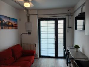 sala de estar con sofá rojo frente a una puerta en La Casita de Vicálvaro, en Madrid