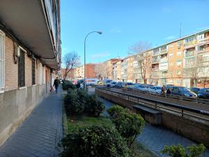 a city street with cars parked next to a canal at La Casita de Vicálvaro in Madrid