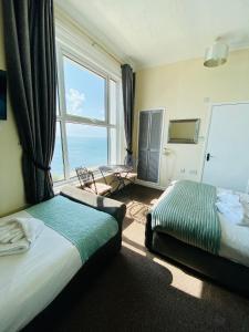 a hotel room with two beds and a large window at Villa Mentone Hotel in Shanklin