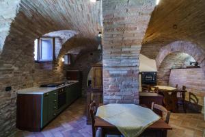 a kitchen with stone walls and a table in a room at B&B La Locanda del Serafino in Sarnano