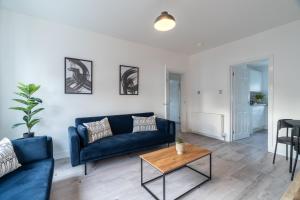 Una sala de estar con un sofá azul y una mesa. en Locksley House, en Knightswood
