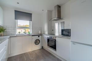 a white kitchen with a washer and dryer at Locksley House in Knightswood
