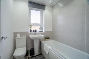 a bathroom with a white tub and a sink and a toilet at Locksley House in Knightswood