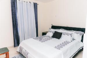 a bedroom with a white bed with black and white pillows at Luxury 2 Bedroom with Pool & Hot-tub in Santo Domingo