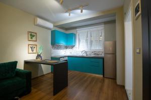 a kitchen with blue cabinets and a green chair at Melnaz Apartament 2 in Korçë
