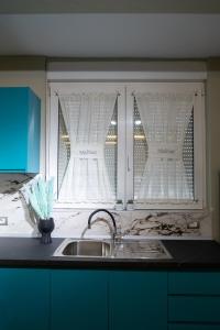 a kitchen with a sink and a window with curtains at Melnaz Apartament 2 in Korçë