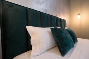 a bed with four pillows and a green headboard at Melnaz Apartament 2 in Korçë +5 photos
