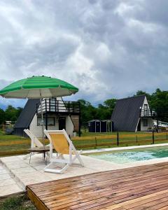 a green umbrella and a chair next to a pool at COMPLEJO ISABELLA in Villa Amancay
