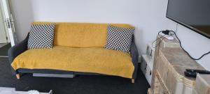 a couch with a yellow blanket in a room at 2 Bed Flat North London in Edmonton