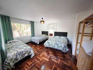 sypialnia z 2 łóżkami i drewnianą podłogą w obiekcie Casa Alpaca w Cuzco