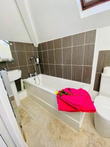 un baño con una bañera blanca y una bolsa rosa. en Villa Mentone Hotel en Shanklin