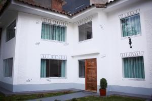 Biały dom z drewnianymi drzwiami i oknami w obiekcie Casa Alpaca w Cuzco