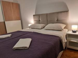 sypialnia z dużym łóżkiem z fioletową pościelą i poduszkami w obiekcie Apartman Zuki w Zagrzebiu