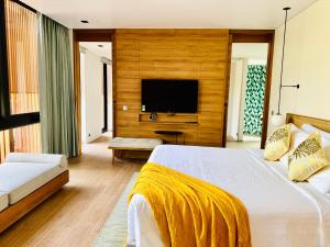 a bedroom with a bed and a tv on a wall at Lucie Villa Phu Quoc - 4 Bedroomss in Phú Quốc