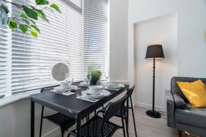 Dyke Apartment في أودينغستن: طاولة طعام مع كراسي ونافذة مع ستائر