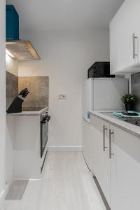 a kitchen with white cabinets and a black bird on the counter at Dyke Apartment in Uddingston