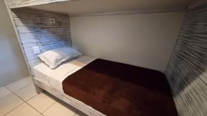 uma pequena cama num quarto com uma janela em Arte da Tribo Hostel & Camping na Praia do Rosa