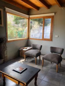 sala de estar con 2 sillas, mesa y ventana en El Tranco - Casa "Bajada Poujardieu" en Junín de los Andes