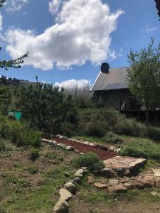 un giardino con rocce e una casa sullo sfondo di El Tranco - Casa "Bajada Poujardieu" a Junín de los Andes