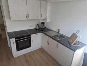 a small kitchen with white cabinets and a sink at Seeperle Souterrain in Sonthofen +9 photos