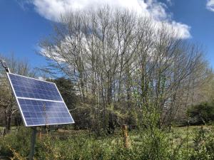 un panel solar sentado en un campo junto a un árbol en El Tranco - Casa "Bajada Poujardieu" en Junín de los Andes