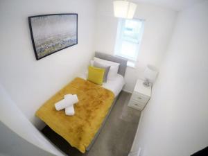 a small white room with a bed with a yellow blanket at Gorgeous 3 bed house in Bristol in Bristol