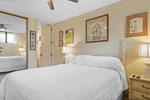 a bedroom with a large white bed and a mirror at Maui Parkshore 209 - MCH in Kihei