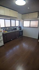 an empty room with a kitchen with wooden floors and windows at ぷらっと赤見 in Sano