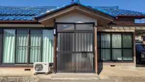 una casa con una puerta con un ventilador delante en ぷらっと赤見, en Sano