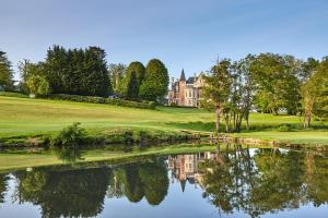 a house on a golf course with a reflection in the water at La perle de Houlgate in Houlgate