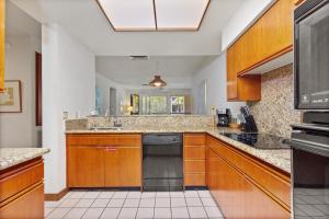 a kitchen with wooden cabinets and a black dishwasher at Shores at Waikoloa 112 - MCH in Waikoloa
