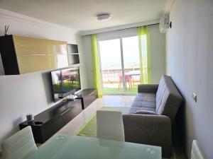 uma sala de estar com um sofá e uma televisão em Sunset 408 heated pool with views em Adeje